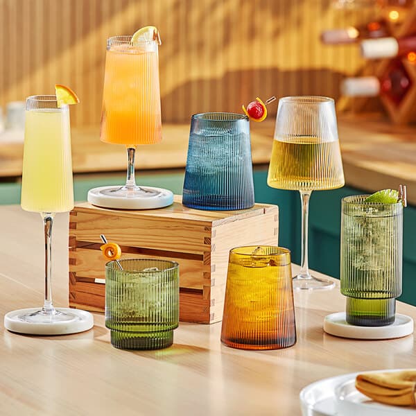 A table with a group of Acopa Lore green stemless wine glasses filled with yellow liquid.