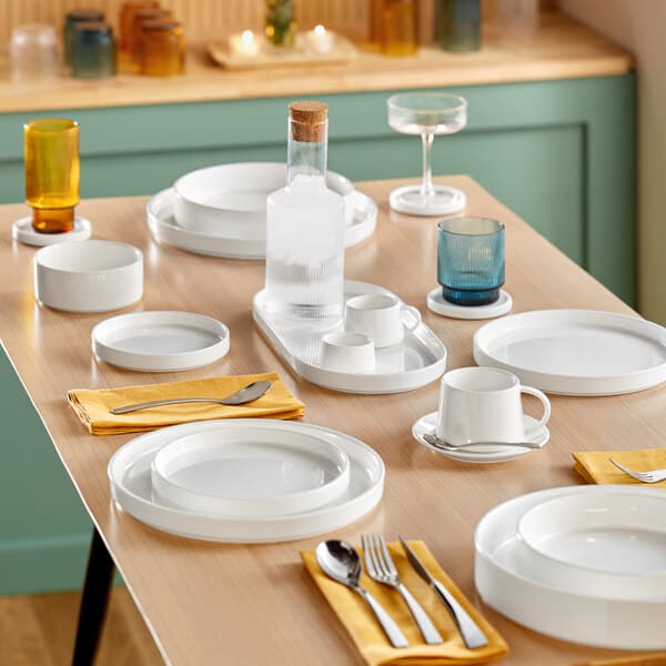 Acopa Lore stemless wine glasses and white plates and glasses on a table.