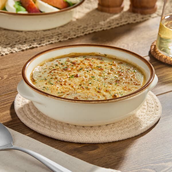 A vanilla bean porcelain onion soup crock filled with baked soup and topped with melted cheese.
