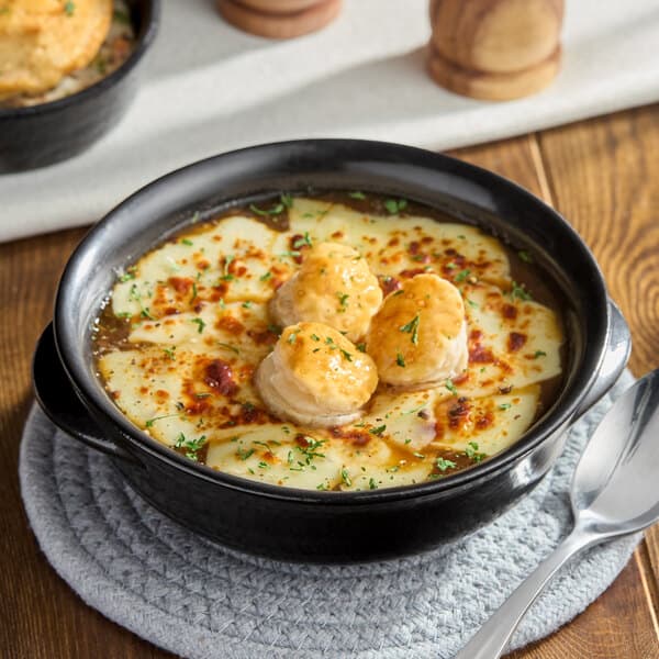 An Acopa Keystone porcelain onion soup crock filled with French onion soup and melted cheese.
