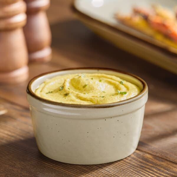 A granite gray Acopa Keystone porcelain ramekin filled with yellow hummus on a table.