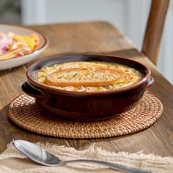 A table set with a bowl of Acopa Keystone chestnut porcelain onion soup with bread.