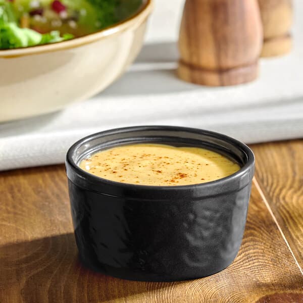 A small black porcelain ramekin filled with a creamy sauce or dressing.