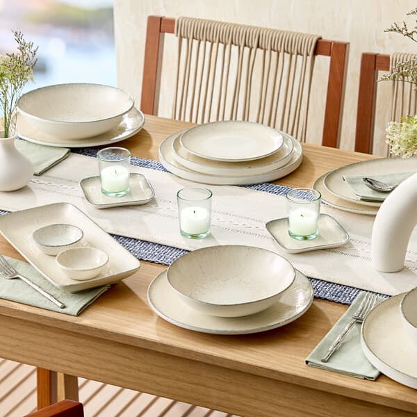 A set of round gray stackable porcelain plates arranged on a dining table.