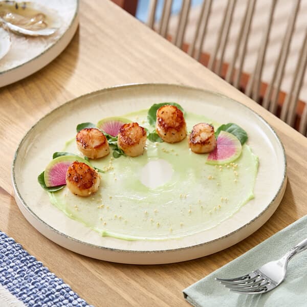 A round gray porcelain plate with a slightly raised rim, shown with a gourmet food presentation.
