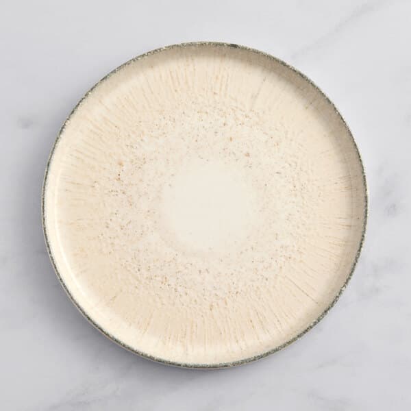 An Acopa Cape porcelain plate with a speckled rim.