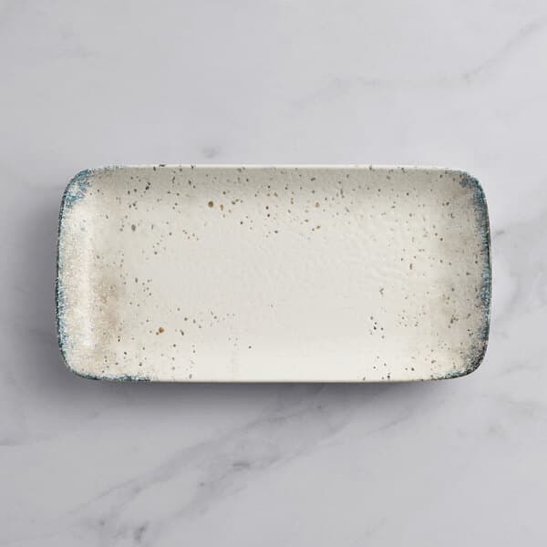 A rectangular white porcelain platter with blue speckles.