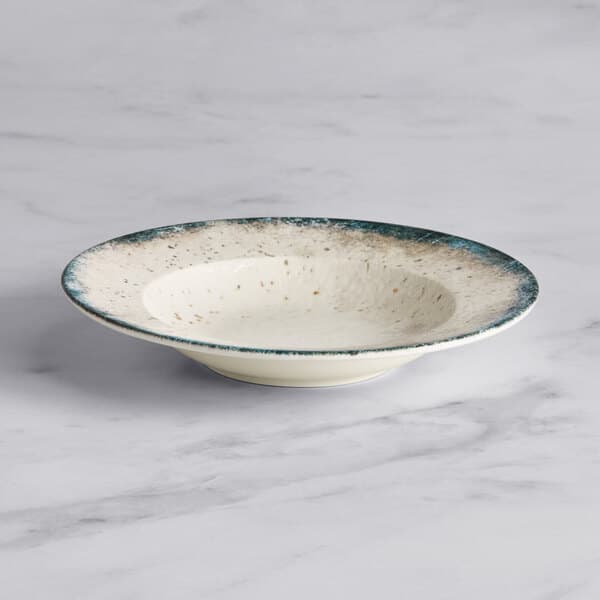An Acopa Architect white porcelain bowl with blue specks.
