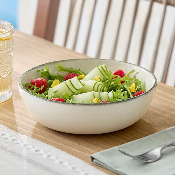 A round gray porcelain bowl filled with salad, placed on a wooden table.