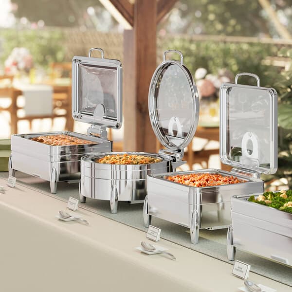An outdoor buffet table with Acopa Manchester chafers holding food.