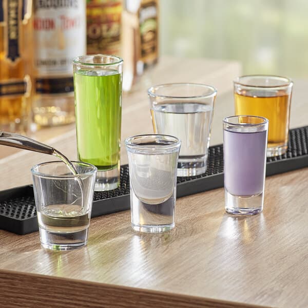 A table in a cocktail bar with several Acopa shot glasses filled with purple liquid.